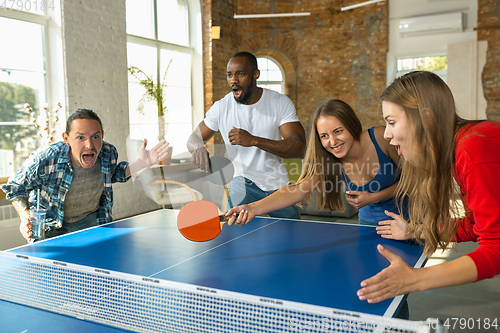 Image of Young people playing table tennis in workplace, having fun