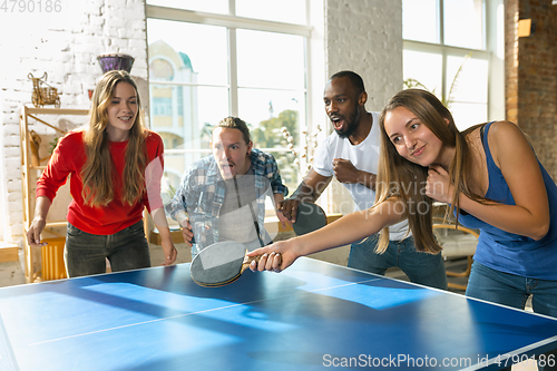 Image of Young people playing table tennis in workplace, having fun