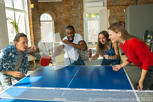 Image of Young people playing table tennis in workplace, having fun