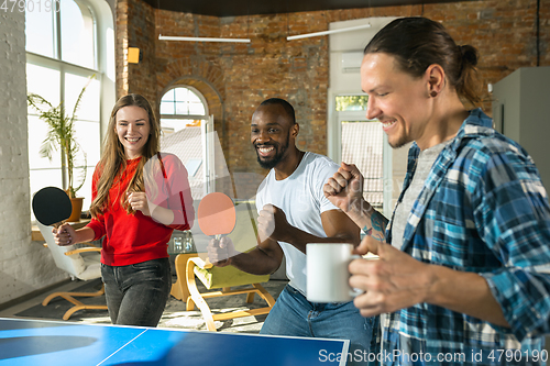 Image of Young people playing table tennis in workplace, having fun