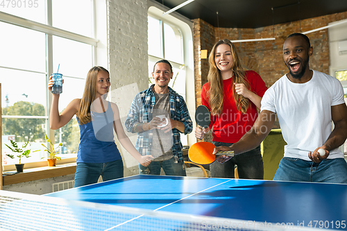 Image of Young people playing table tennis in workplace, having fun