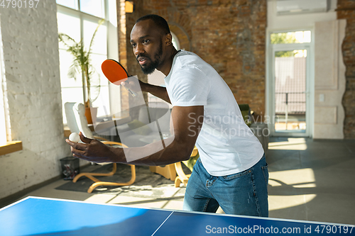 Image of Young man playing table tennis in workplace, having fun