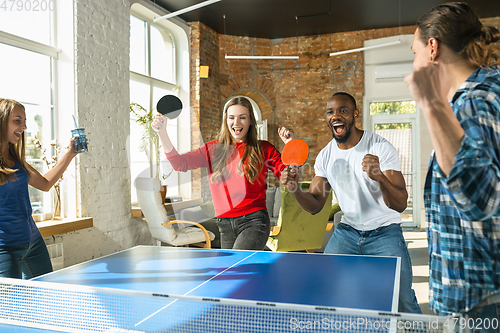 Image of Young people playing table tennis in workplace, having fun