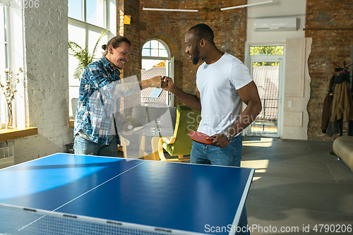 Image of Young men playing table tennis in workplace, having fun