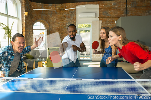 Image of Young people playing table tennis in workplace, having fun