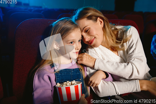 Image of Young caucasian mother and daughter watching a film at a movie theater