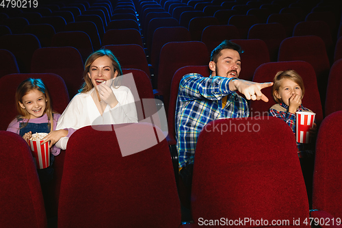 Image of Young caucasian family watching a film at a movie theater