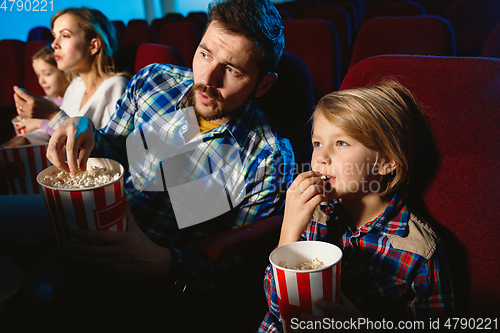 Image of Young caucasian family watching a film at a movie theater