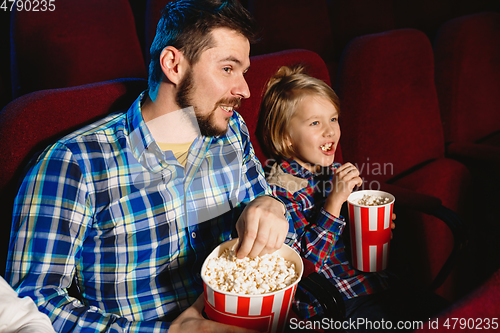 Image of Young caucasian father and son watching a film at a movie theater