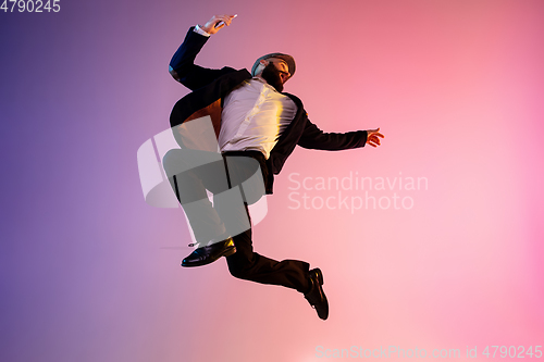 Image of Full length portrait of happy jumping man in neon light and gradient background