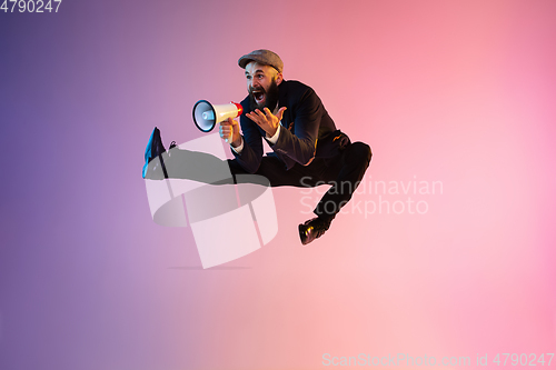 Image of Full length portrait of happy jumping man in neon light and gradient background