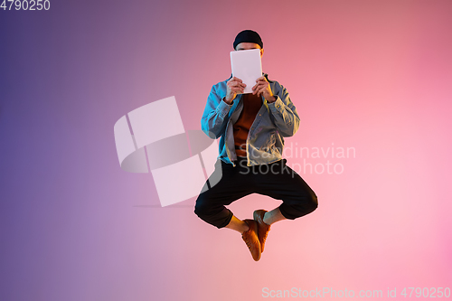 Image of Full length portrait of happy jumping man in neon light and gradient background