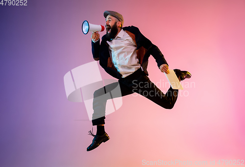 Image of Full length portrait of happy jumping man in neon light and gradient background