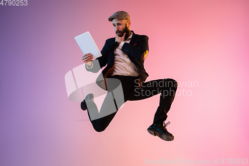 Image of Full length portrait of happy jumping man in neon light and gradient background