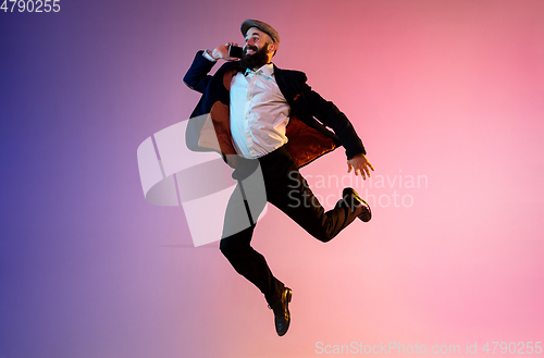 Image of Full length portrait of happy jumping man in neon light and gradient background