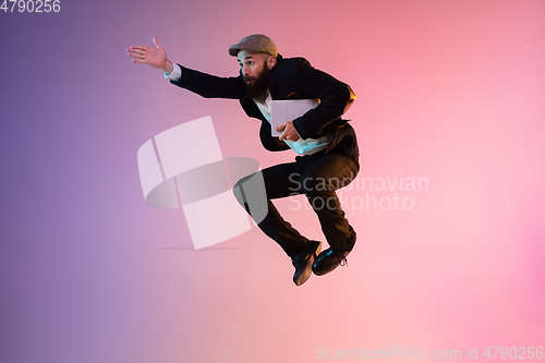 Image of Full length portrait of happy jumping man in neon light and gradient background