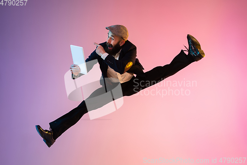 Image of Full length portrait of happy jumping man in neon light and gradient background