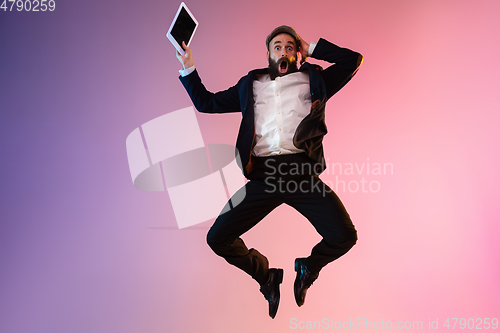 Image of Full length portrait of happy jumping man in neon light and gradient background