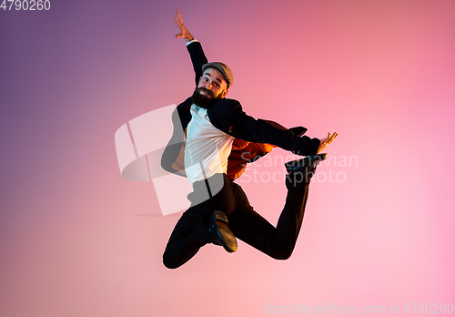 Image of Full length portrait of happy jumping man in neon light and gradient background