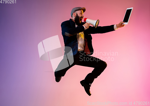 Image of Full length portrait of happy jumping man in neon light and gradient background