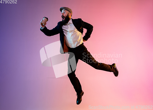 Image of Full length portrait of happy jumping man in neon light and gradient background