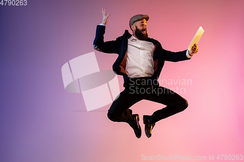 Image of Full length portrait of happy jumping man in neon light and gradient background