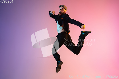 Image of Full length portrait of happy jumping man in neon light and gradient background