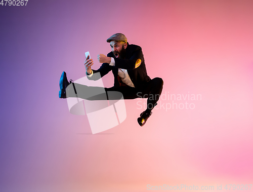 Image of Full length portrait of happy jumping man in neon light and gradient background