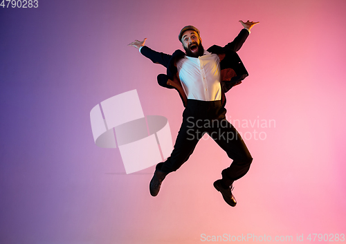 Image of Full length portrait of happy jumping man in neon light and gradient background