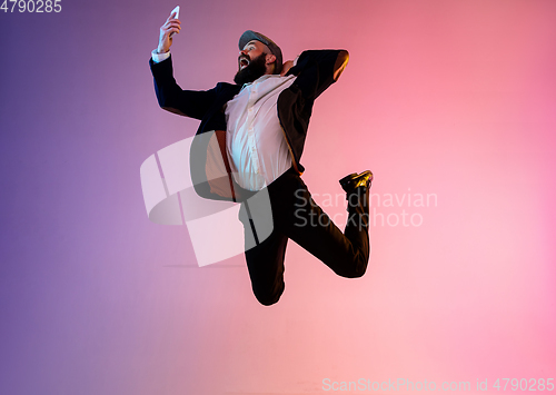 Image of Full length portrait of happy jumping man in neon light and gradient background