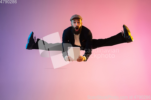 Image of Full length portrait of happy jumping man in neon light and gradient background