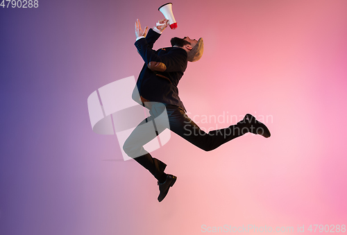 Image of Full length portrait of happy jumping man in neon light and gradient background