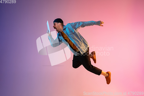 Image of Full length portrait of happy jumping man in neon light and gradient background