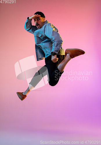 Image of Full length portrait of happy jumping man in neon light and gradient background