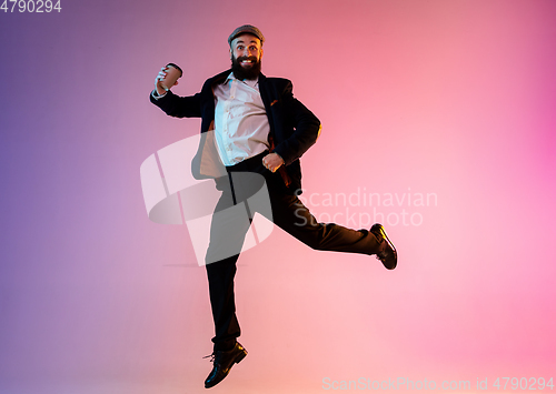 Image of Full length portrait of happy jumping man in neon light and gradient background