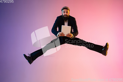 Image of Full length portrait of happy jumping man in neon light and gradient background