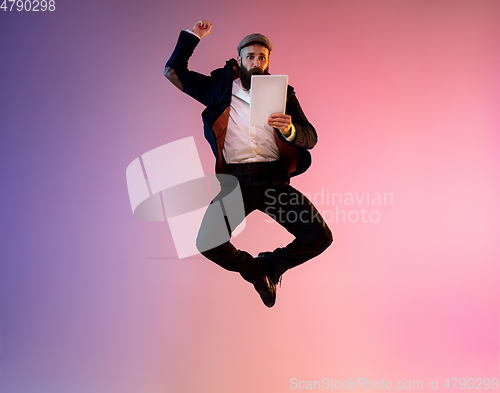 Image of Full length portrait of happy jumping man in neon light and gradient background