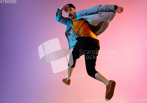 Image of Full length portrait of happy jumping man in neon light and gradient background