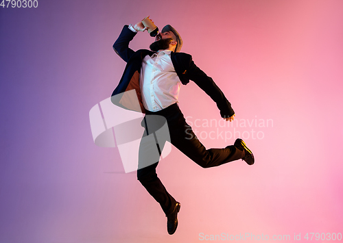 Image of Full length portrait of happy jumping man in neon light and gradient background