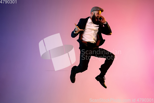 Image of Full length portrait of happy jumping man in neon light and gradient background