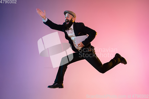 Image of Full length portrait of happy jumping man in neon light and gradient background