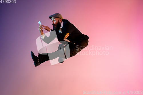 Image of Full length portrait of happy jumping man in neon light and gradient background