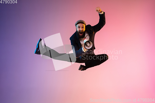 Image of Full length portrait of happy jumping man in neon light and gradient background