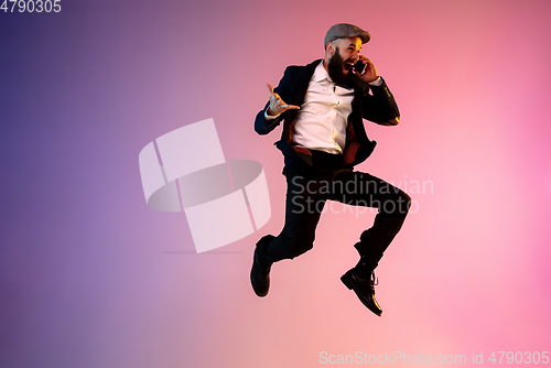 Image of Full length portrait of happy jumping man in neon light and gradient background