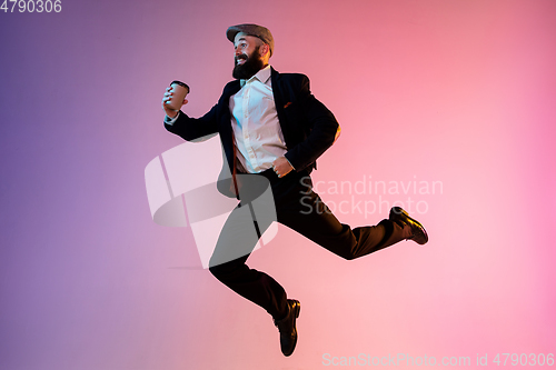 Image of Full length portrait of happy jumping man in neon light and gradient background