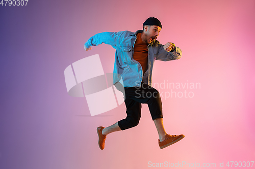 Image of Full length portrait of happy jumping man in neon light and gradient background