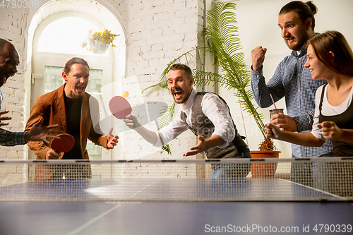 Image of Young people playing table tennis in workplace, having fun