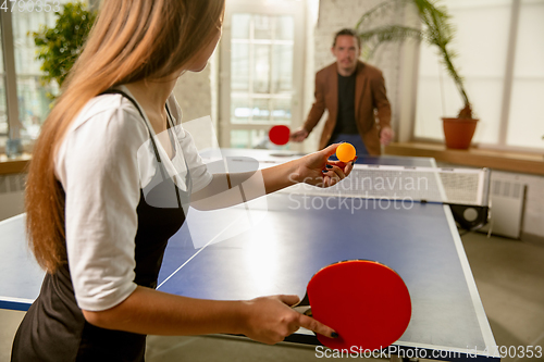 Image of Young people playing table tennis in workplace, having fun