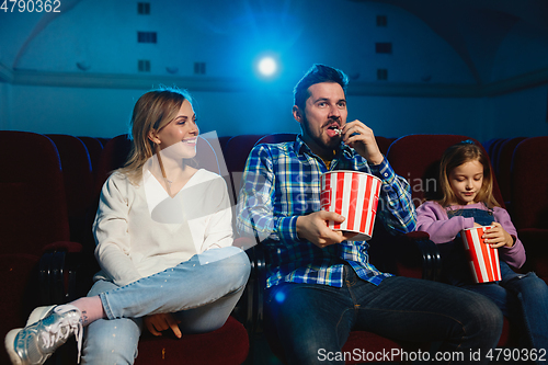 Image of Young caucasian family watching a film at a movie theater