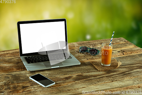 Image of Blank laptop on a wooden table outdoors, mock up